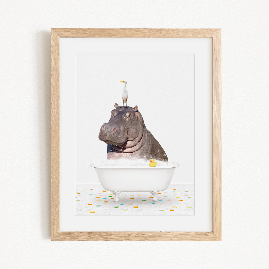 A framed image depicting a hippopotamus sitting in a bathtub, with a bird perched on its head.