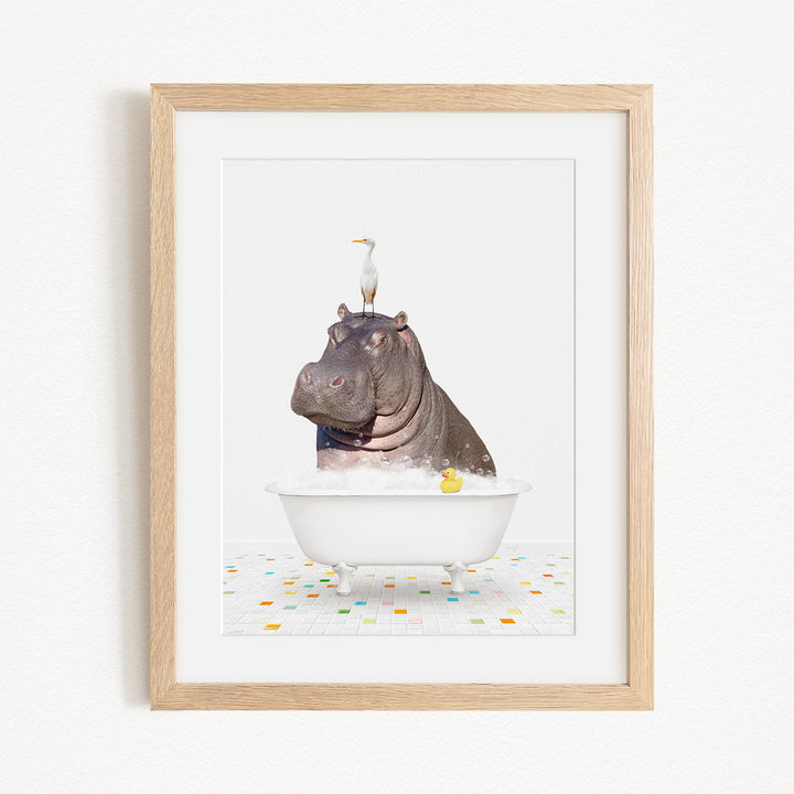 A framed image depicting a hippopotamus sitting in a bathtub, with a bird perched on its head.