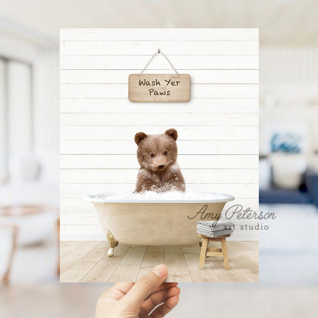 a hand holding a photo of a teddy bear in a bathtub