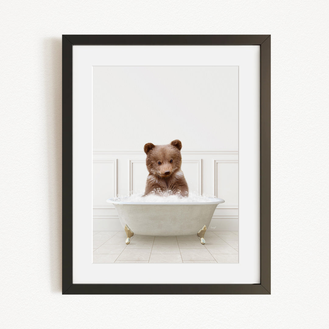A brown bear sitting in a white bathtub filled with bubbles, looking directly at the camera.
