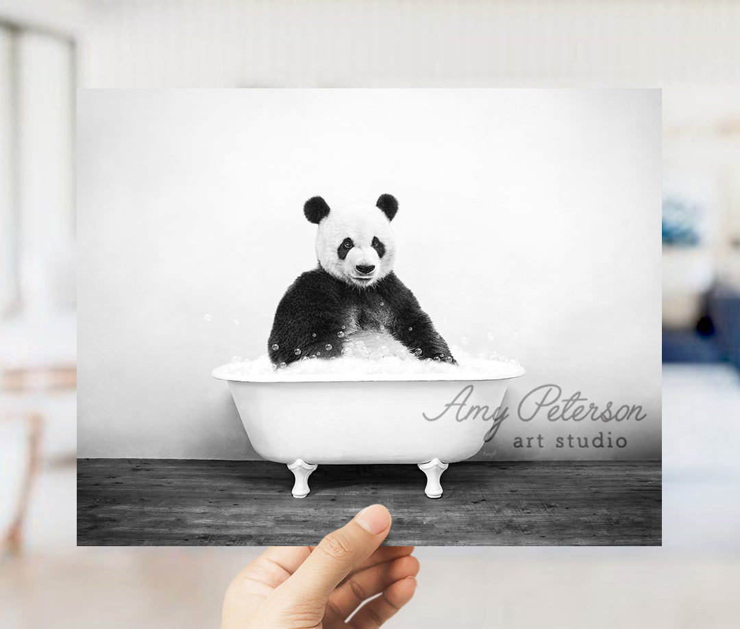 a hand holding up a black and white photo of a panda in a bathtub