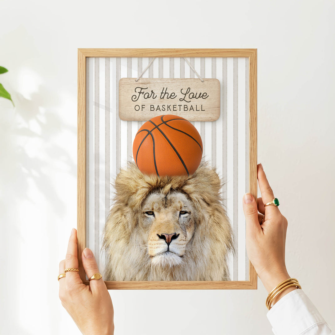 A person's hands are holding a framed picture of a lion with a basketball on its head.