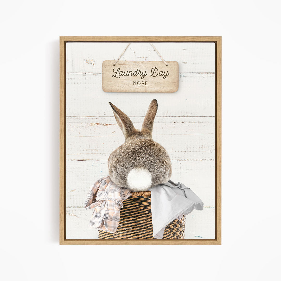 A wooden sign with the text "Laundry Day NOPE" hangs above a basket containing a plaid shirt and a gray garment.