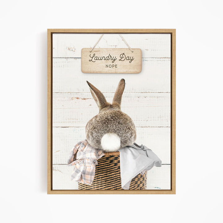 A wooden sign with the text "Laundry Day NOPE" hangs above a basket containing a plaid shirt and a gray garment.