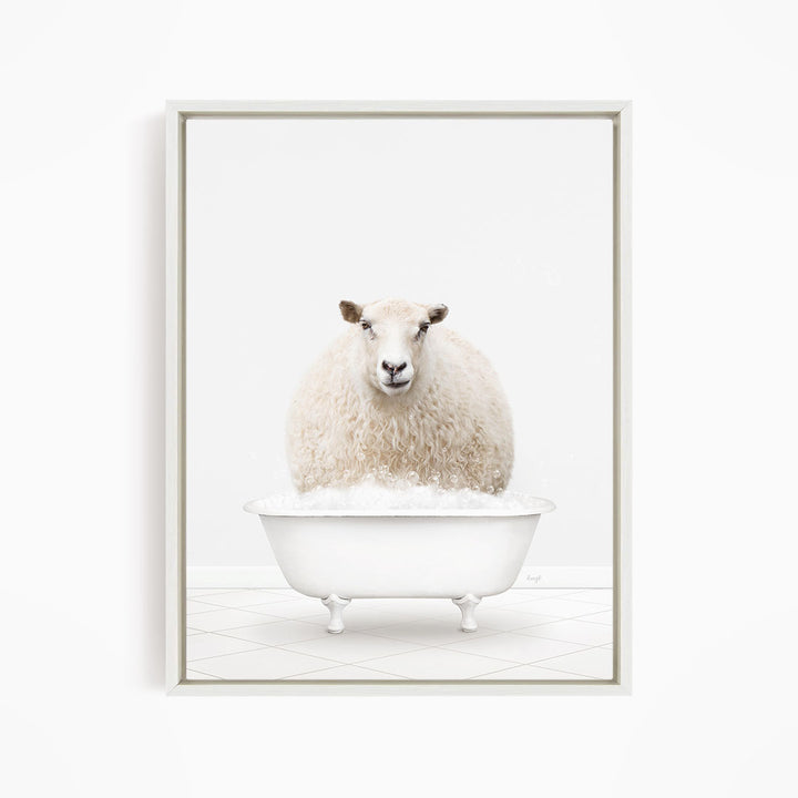 A fluffy white sheep sits in a white bathtub filled with bubbles, looking directly at the camera.