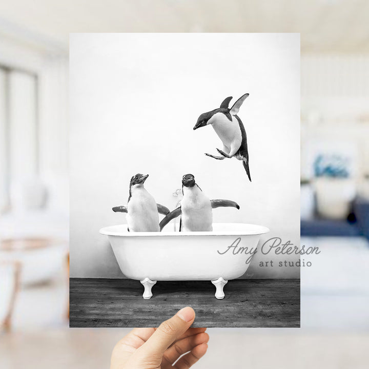 a hand holding up a card with penguins in a bathtub