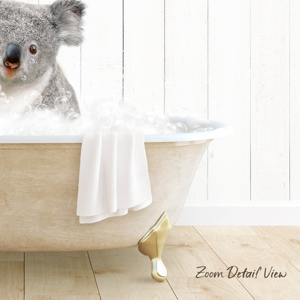 A koala sitting in a bathtub filled with bubbles, with a towel draped over the side of the tub.