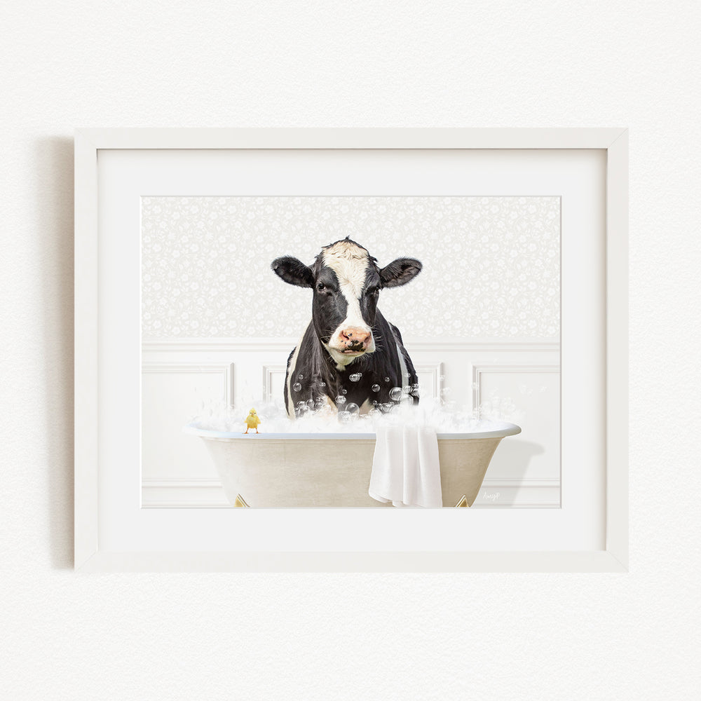 A black and white cow is sitting in a white bathtub filled with bubbles, looking directly at the camera.