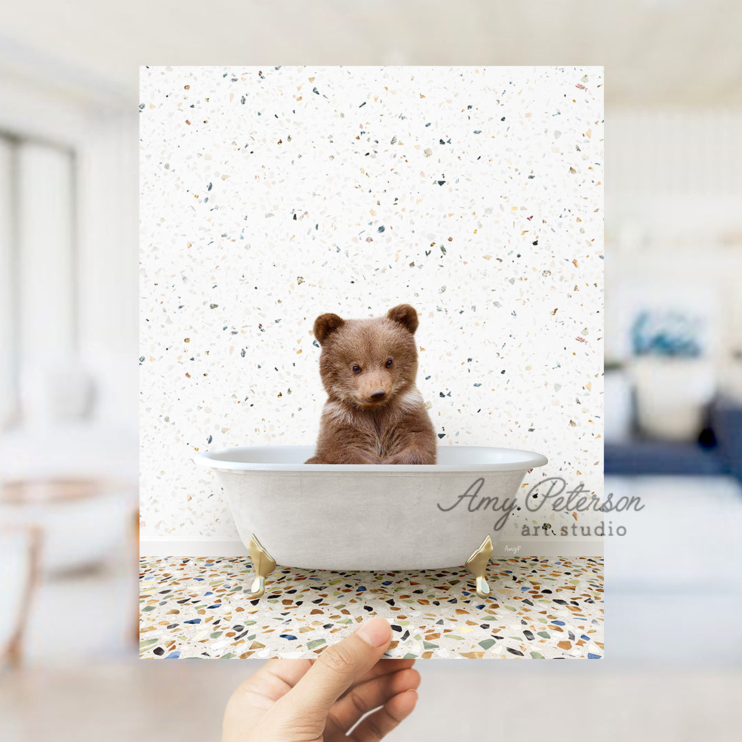 a person holding a polaroid picture of a brown bear in a bathtub