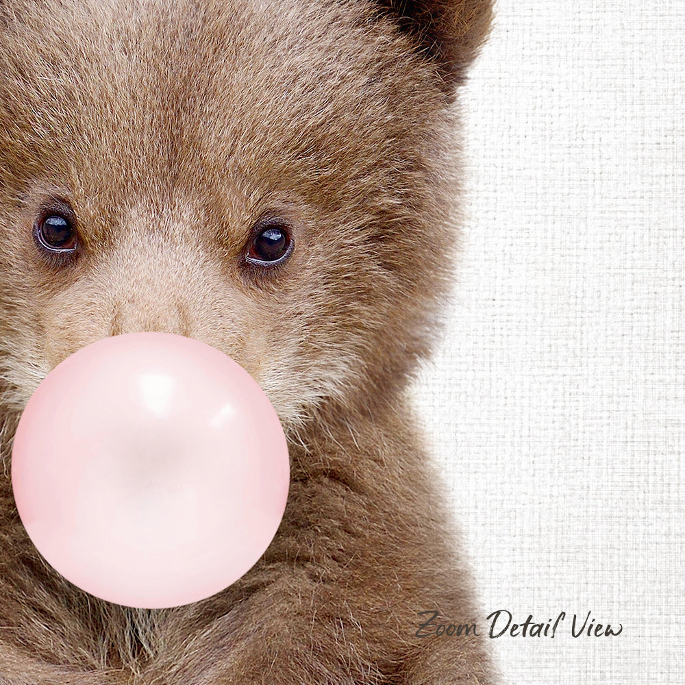 A close-up of a brown bear blowing a pink bubblegum bubble.