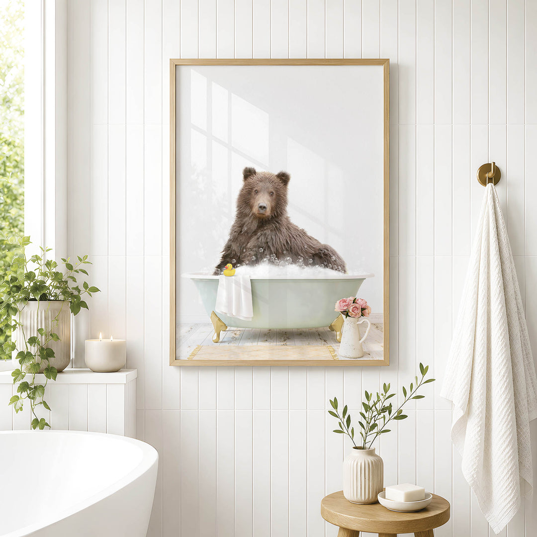 A framed image of a brown bear sitting in a bathtub, surrounded by plants and flowers, in a bathroom setting.
