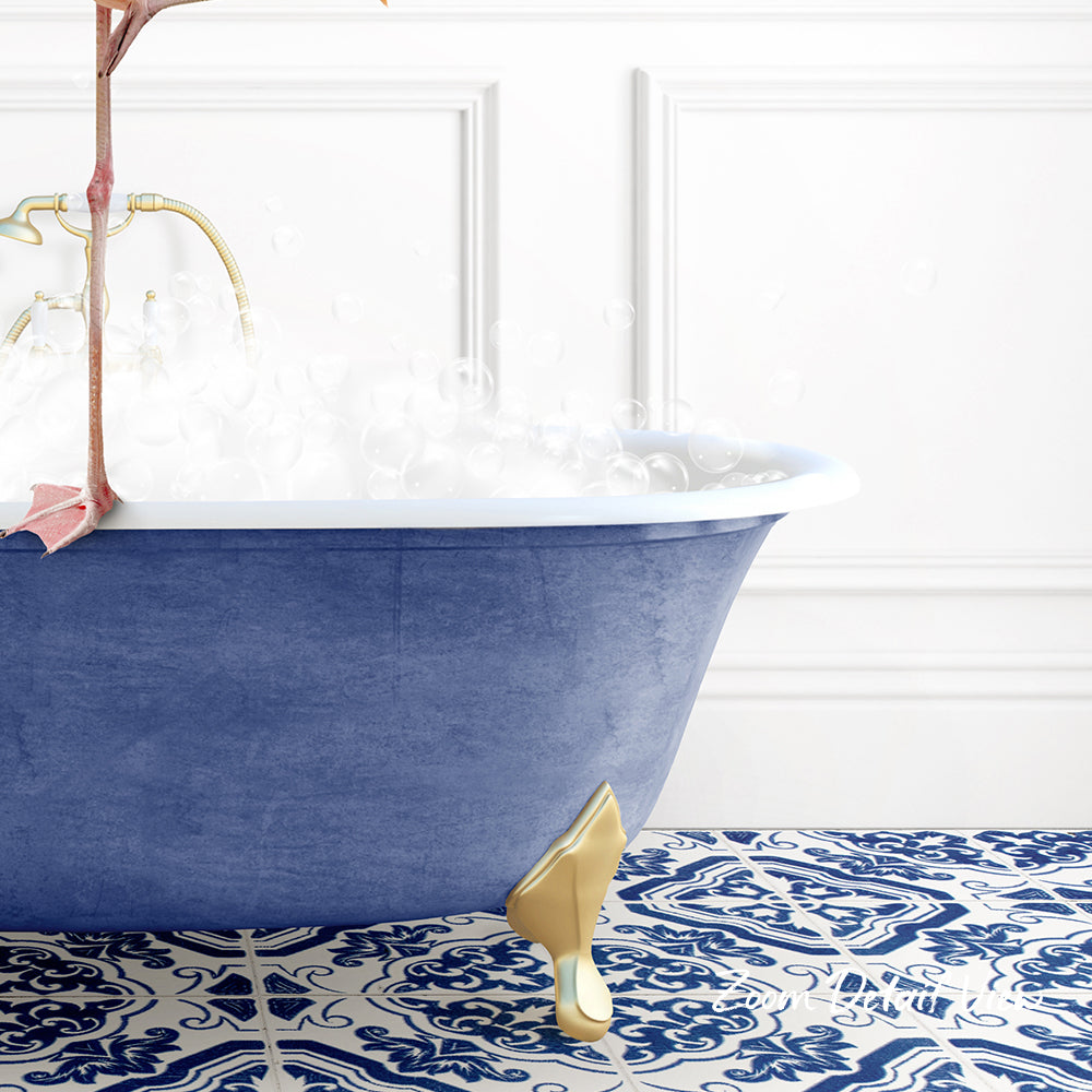A blue clawfoot bathtub filled with water and bubbles, with a gold clawfoot design on the side, set against a white wall with a patterned tile floor.