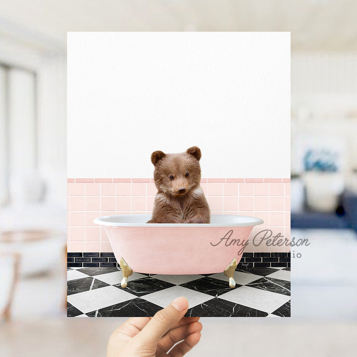 a person holding a card with a picture of a teddy bear in a bathtub