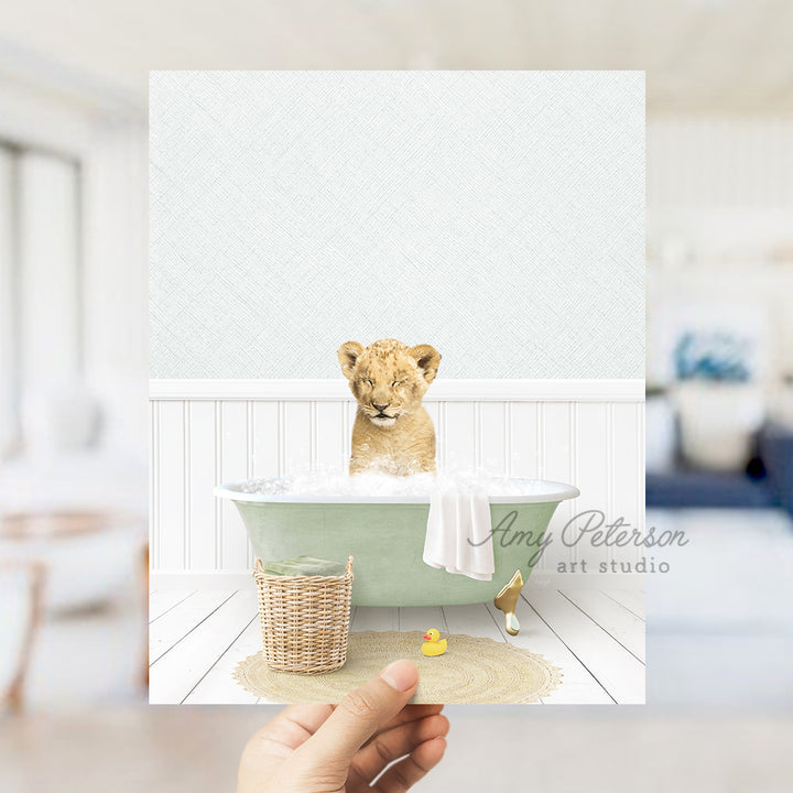 a hand holding a card with a picture of a baby lion in a bathtub