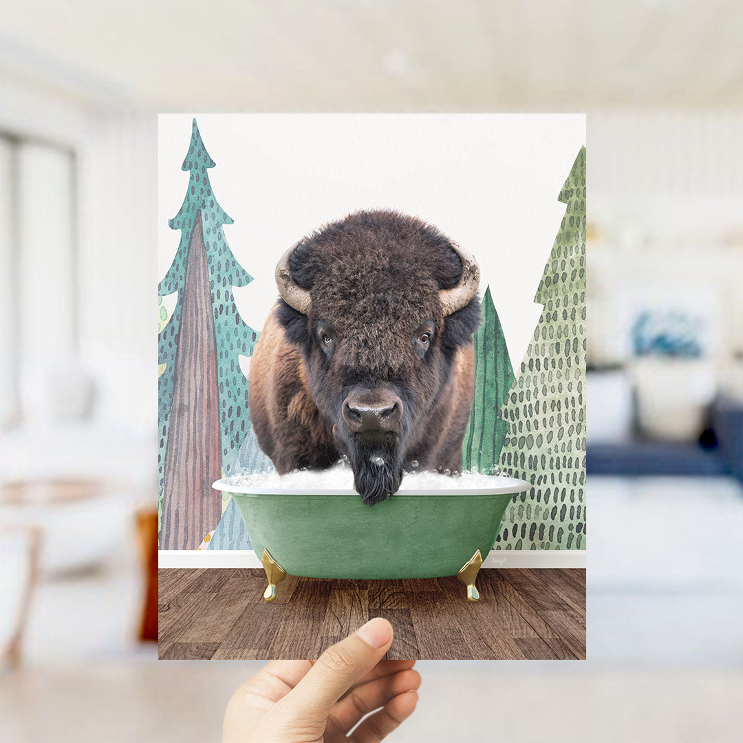 A bison with large horns is sitting in a green bathtub, surrounded by trees and a snowy landscape.