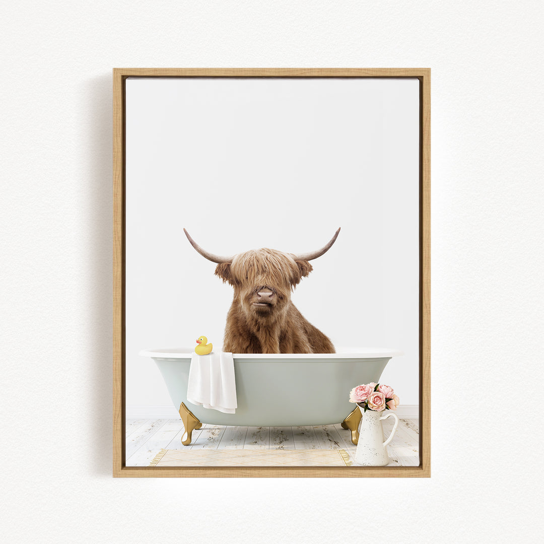 A brown cow with long horns is sitting in a white bathtub, surrounded by a yellow rubber duck and a vase of pink flowers.