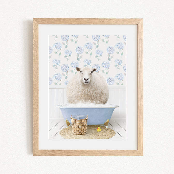 A fluffy white sheep sits in a blue bathtub filled with bubbles, surrounded by a wicker basket and yellow rubber ducks.