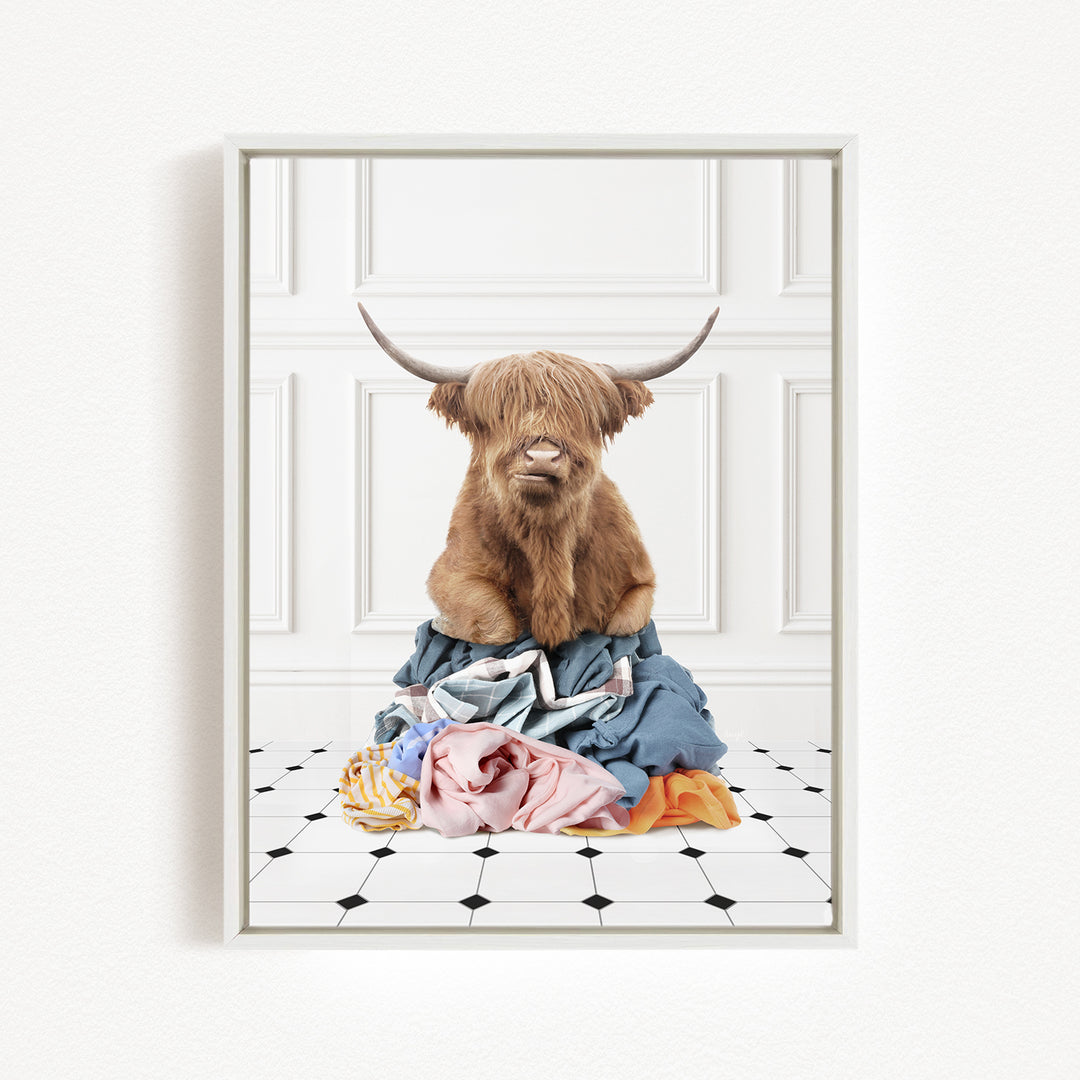 A brown cow with horns is sitting on a pile of clothes on a tiled floor.