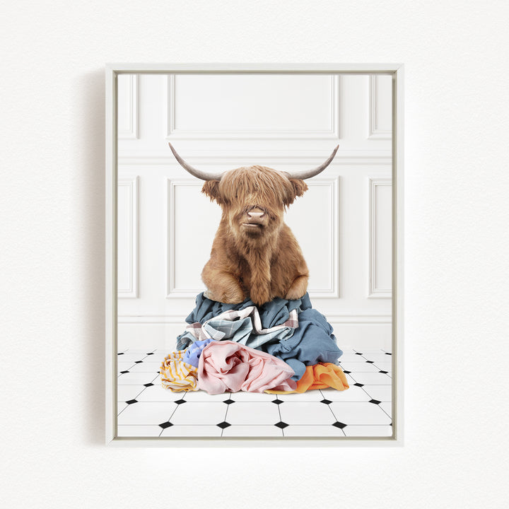 A brown cow with horns is sitting on a pile of clothes on a tiled floor.