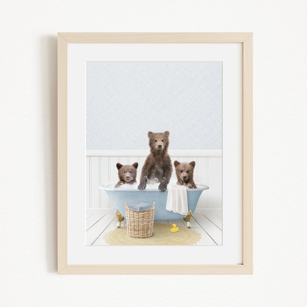 A framed image depicting three bears sitting in a bathtub, with one bear sitting on the edge of the tub and the other two bears sitting inside the tub.