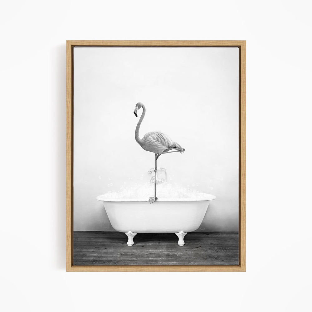 A black and white photograph of a flamingo standing on the edge of a white bathtub filled with water.