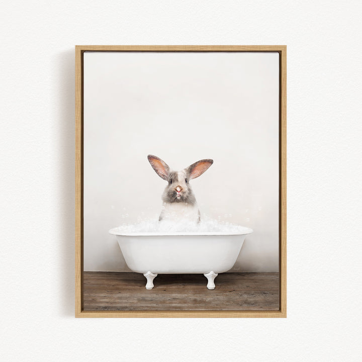 A white rabbit sitting in a white bathtub filled with bubbles, looking directly at the camera.