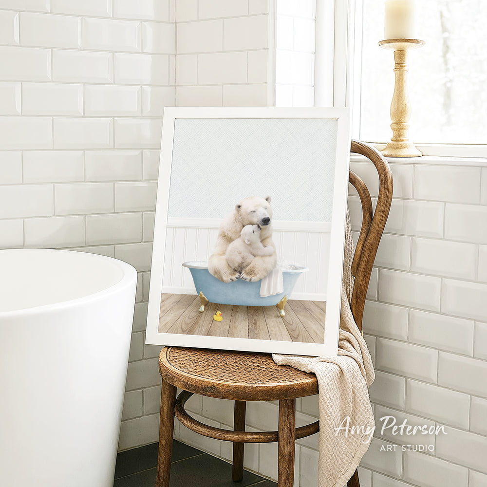 A framed image of two polar bears sitting in a bathtub, with one bear appearing to be hugging the other, is displayed on a wooden chair in a bathroom setting.
