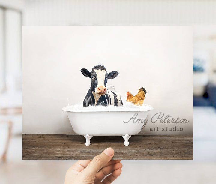 a hand holding up a card with a picture of a cow in a bathtub