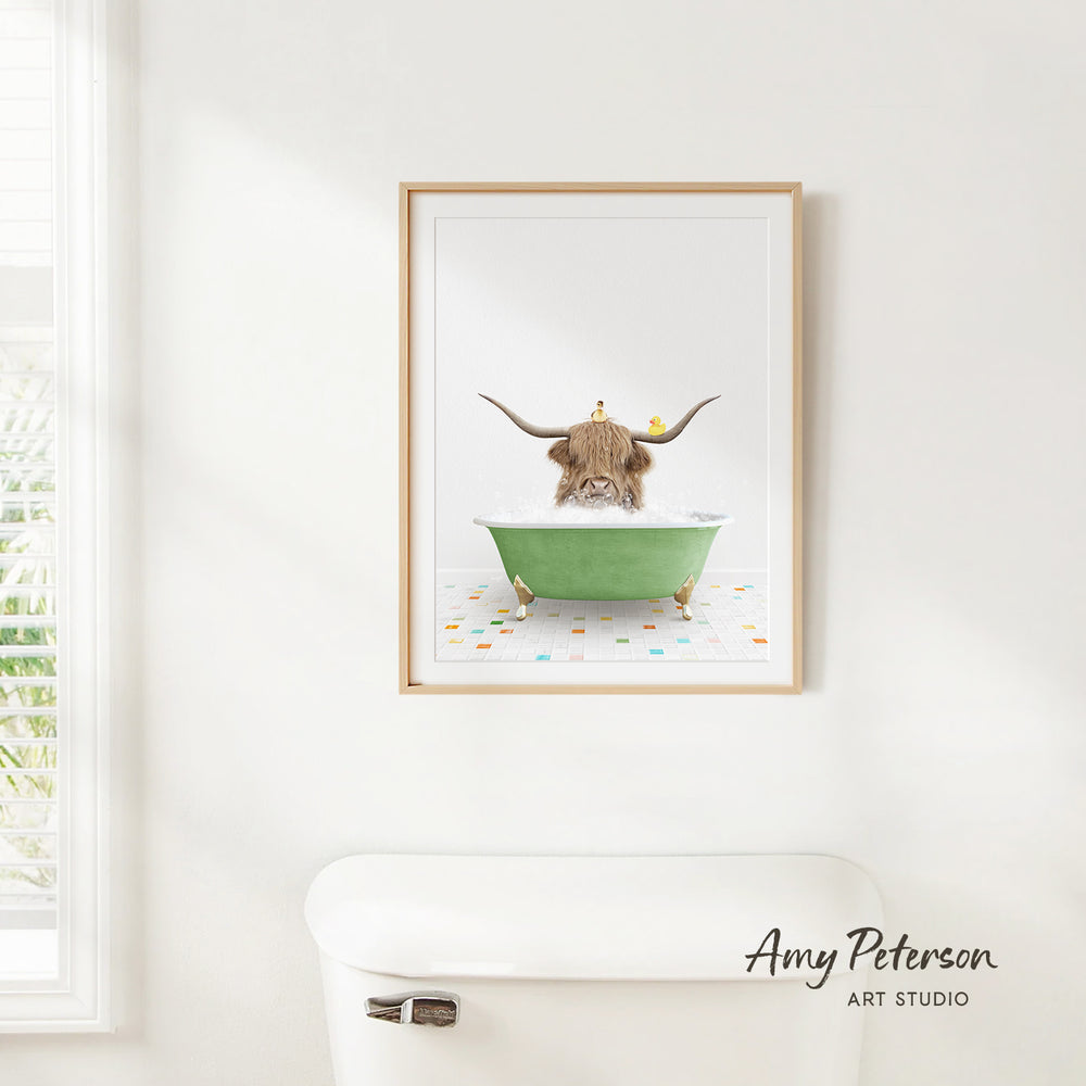 A framed print of a Highland cow sitting in a green bathtub, with a yellow bird perched on its head, is hanging on a white wall.