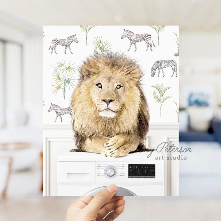 a hand holding a picture of a lion on top of a washing machine