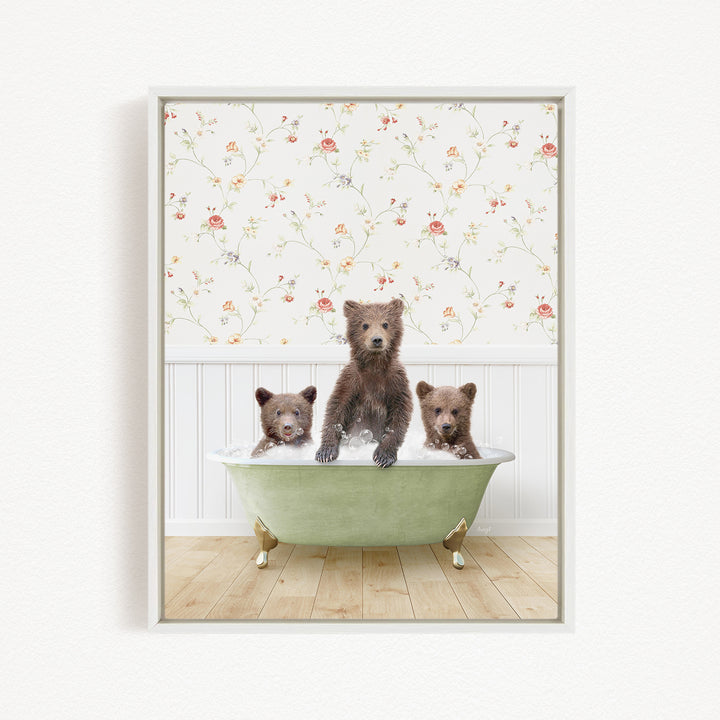 A framed image depicting three brown bears sitting in a green bathtub, with a floral wallpaper in the background.
