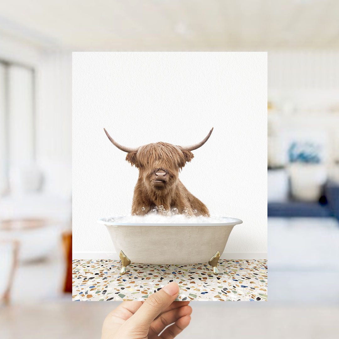 A brown cow with long horns is sitting in a white bathtub filled with water, appearing to enjoy the bath.