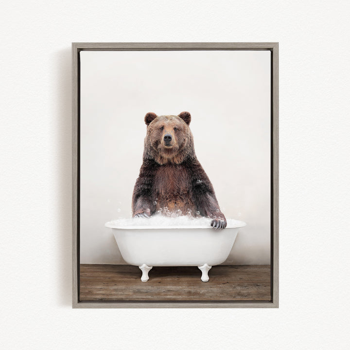 A brown bear sitting in a white bathtub filled with bubbles, appearing to enjoy the bath.