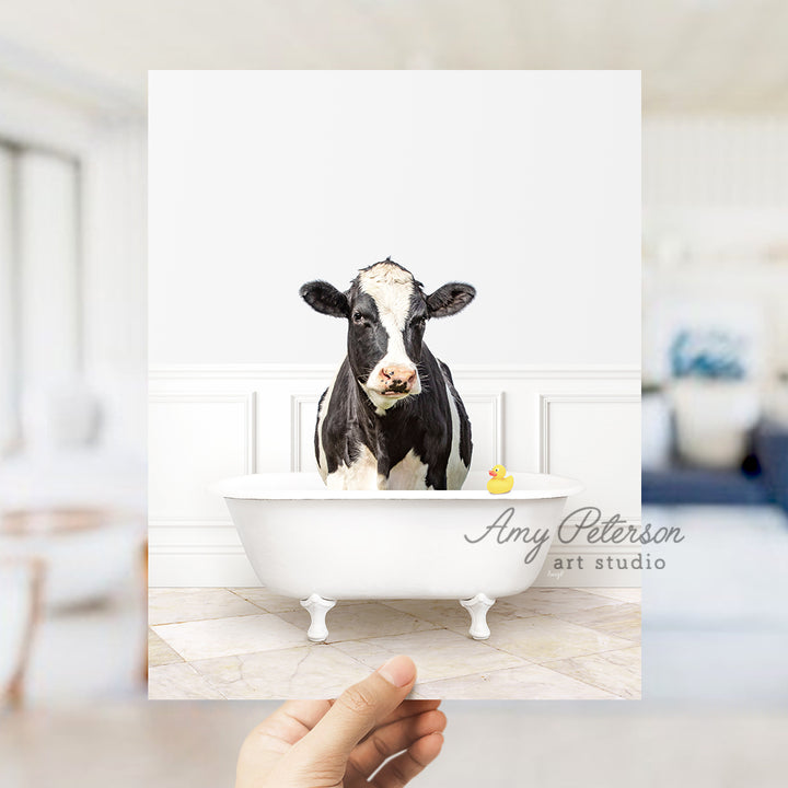 a hand holding up a card with a picture of a cow in a bathtub