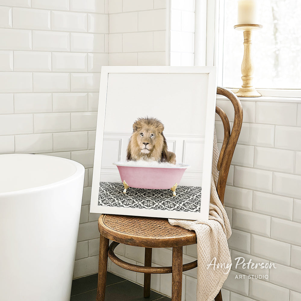 A framed image of a lion sitting in a pink bathtub, with a towel draped over the back of the chair.