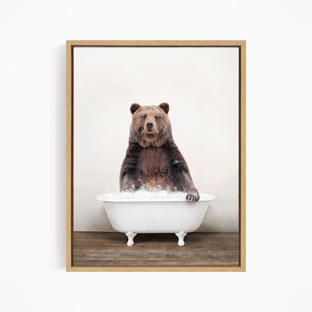 A brown bear sitting in a white bathtub filled with water, appearing to enjoy the bath.