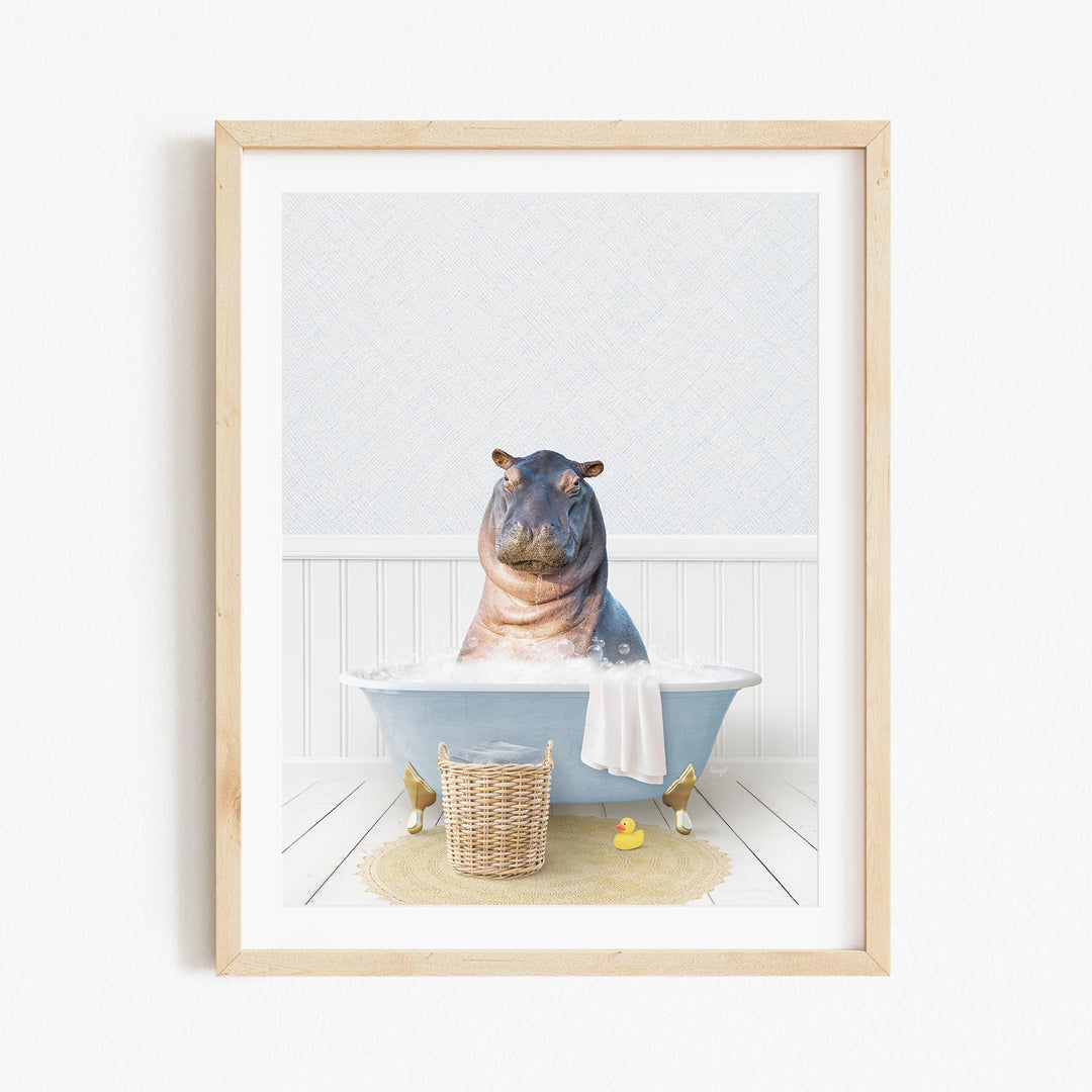 A framed image depicting a hippopotamus sitting in a bathtub filled with water, surrounded by a basket of rubber ducks and a towel.