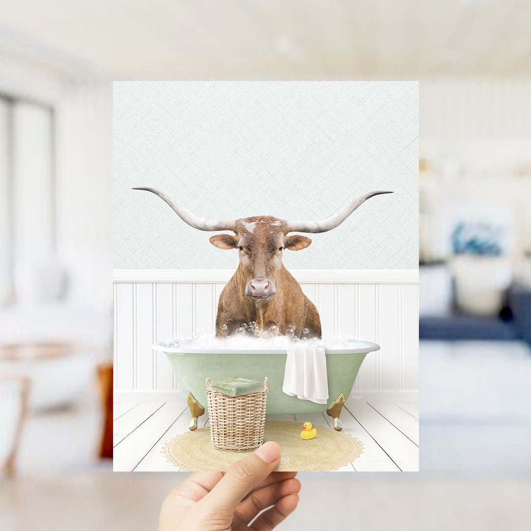 A brown bull with long horns is sitting in a green bathtub filled with bubbles, with a yellow rubber duck nearby.