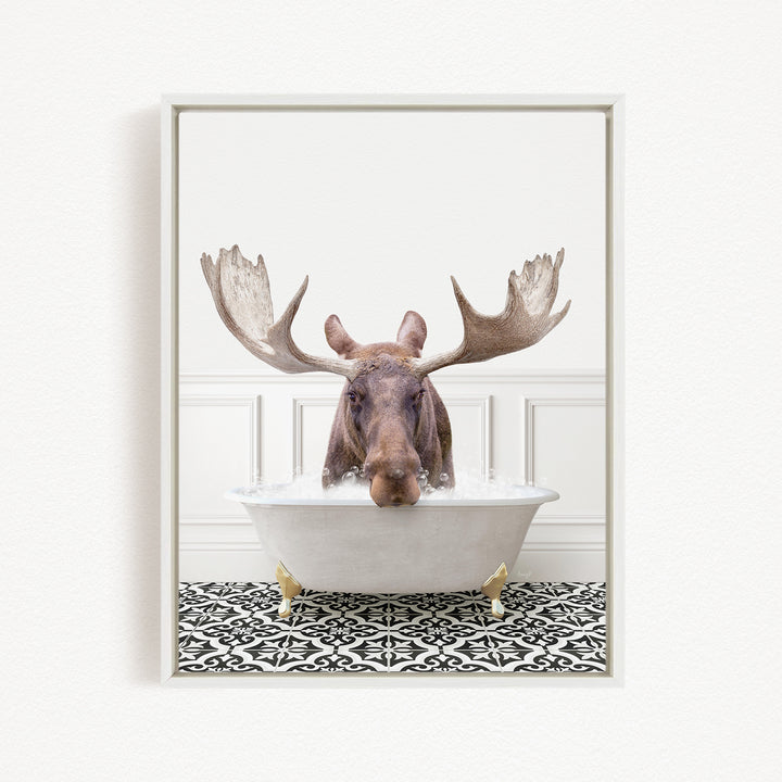 A moose with large antlers is sitting in a white bathtub filled with water, creating a whimsical and humorous scene.
