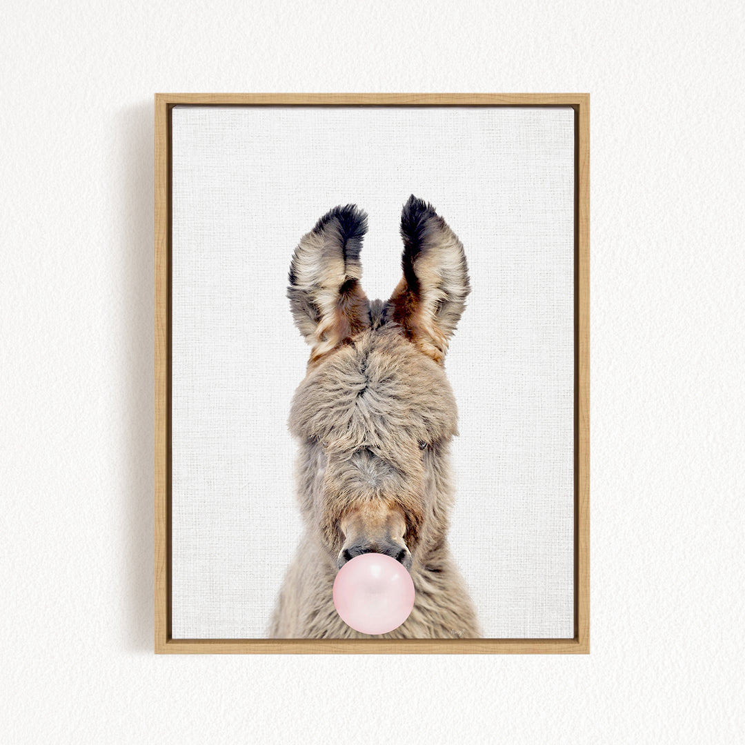 A donkey with its head tilted upwards and a pink bubble gum bubble in its mouth.