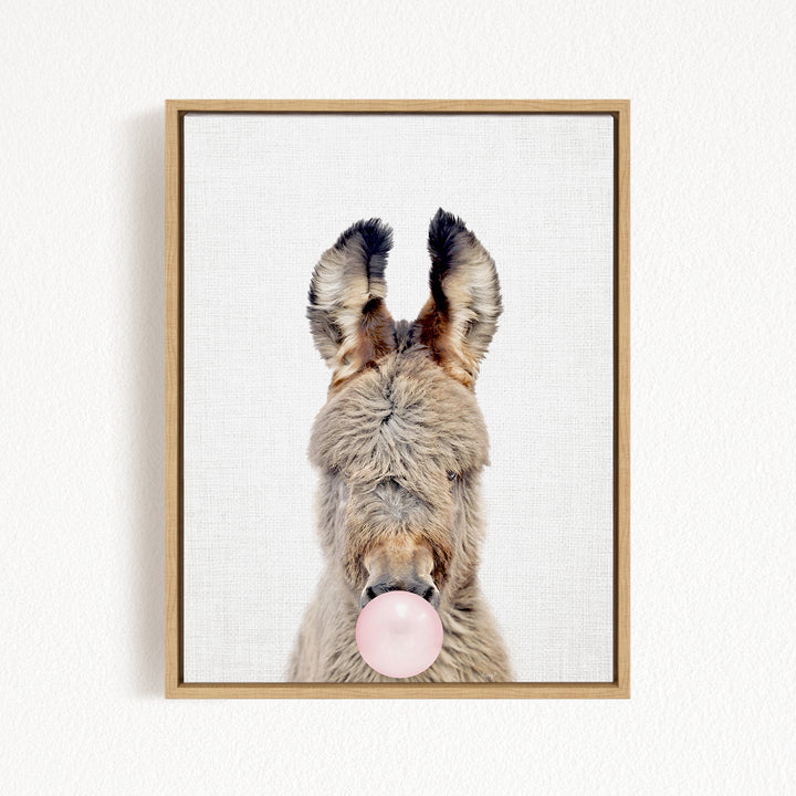 A donkey with its head tilted upwards and a pink bubble gum bubble in its mouth.