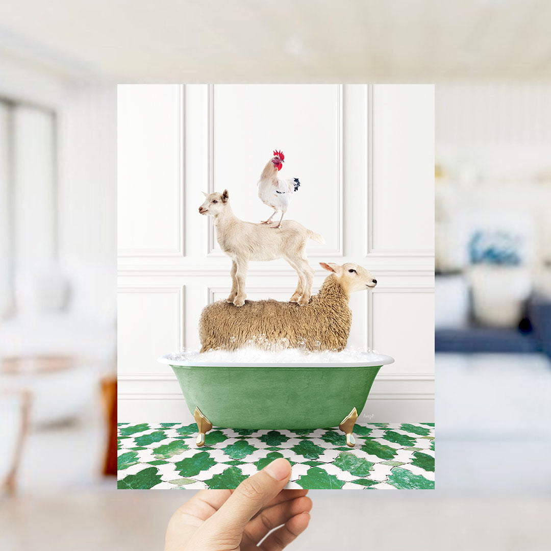 A hand holds up a framed image depicting a goat standing on a sheep's back in a bathtub, with a rooster perched on top.