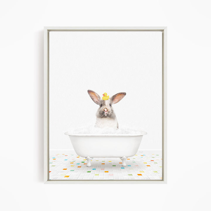 A white rabbit sitting in a white bathtub filled with bubbles, with a yellow rubber duck perched on its head.
