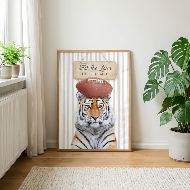 A framed poster of a tiger wearing a football helmet, with the text "For the Love of Football" on it, is displayed on a wall in a room with a rug and potted plants.