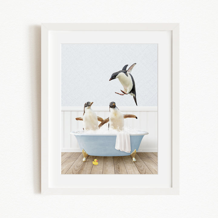 A framed image depicting two penguins sitting in a bathtub, with one penguin flying towards the other.