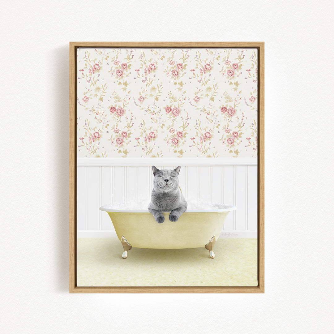 A gray cat sitting in a yellow bathtub filled with bubbles, with a floral wallpaper in the background.