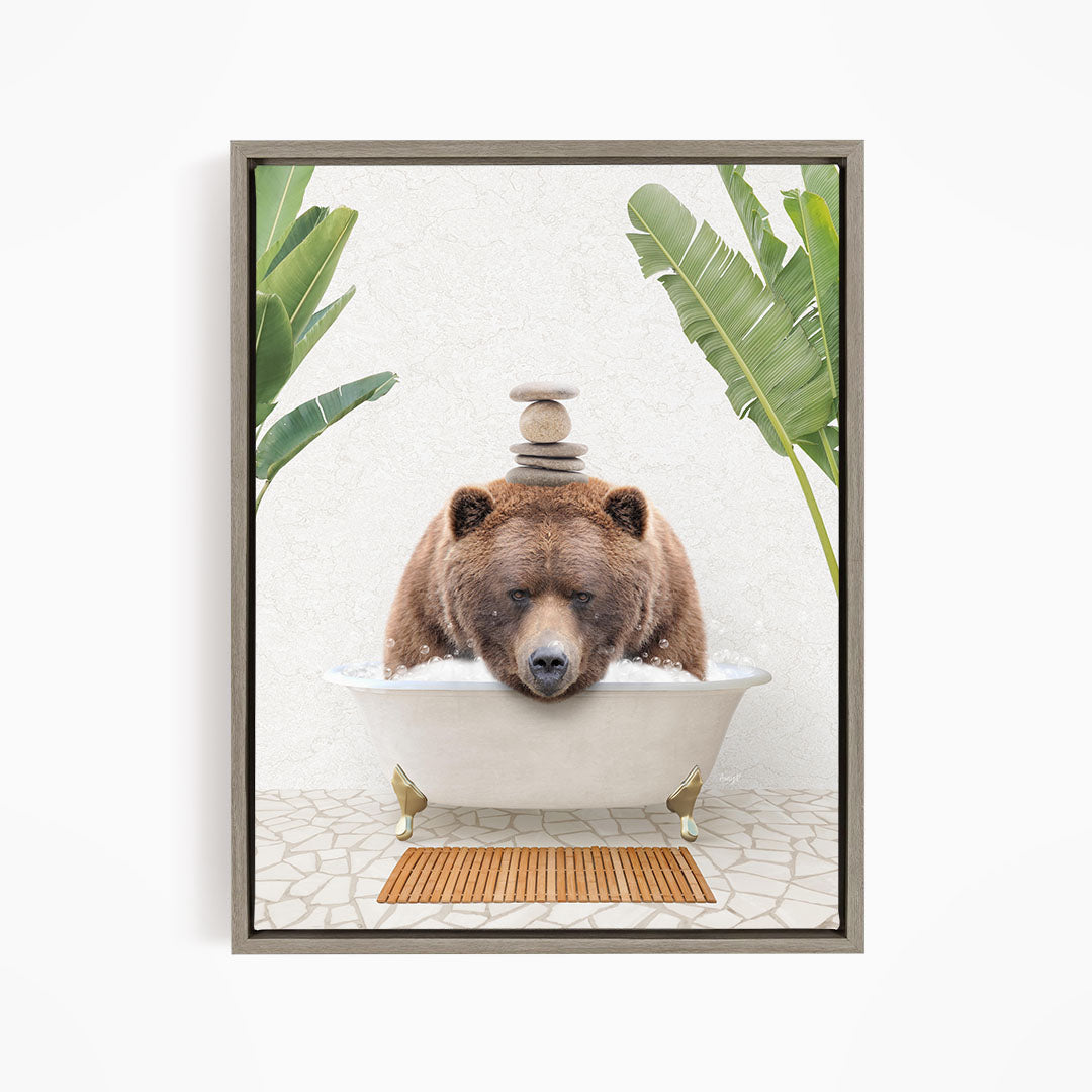 A brown bear is sitting in a bathtub filled with water, surrounded by green plants and a wooden mat on the floor.