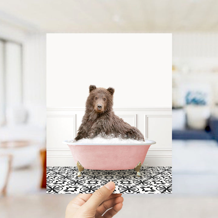 A brown bear sitting in a pink bathtub filled with bubbles, with a black and white patterned floor in the background.
