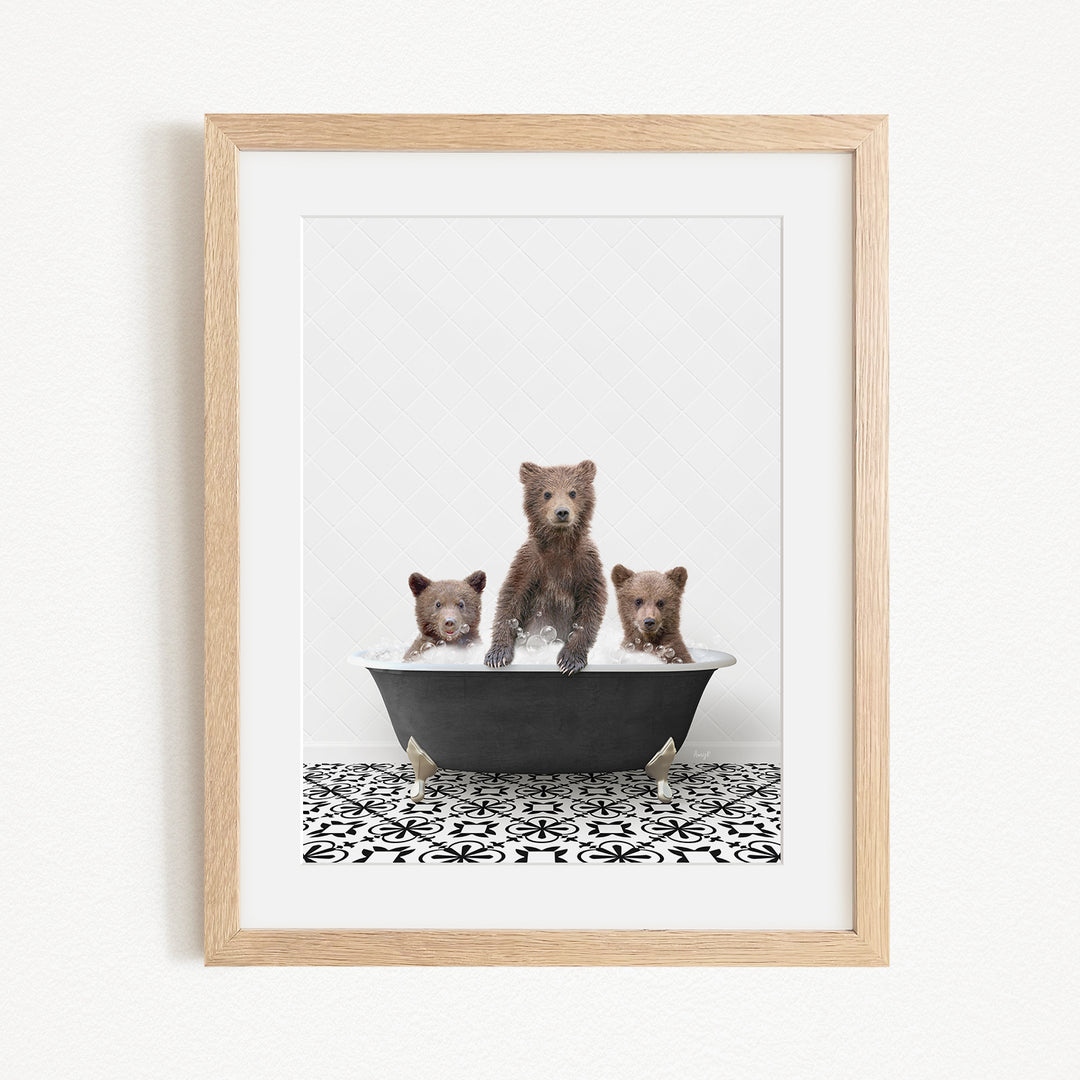 A framed image depicting three bears sitting in a bathtub, with one bear standing on its hind legs and the other two sitting comfortably.