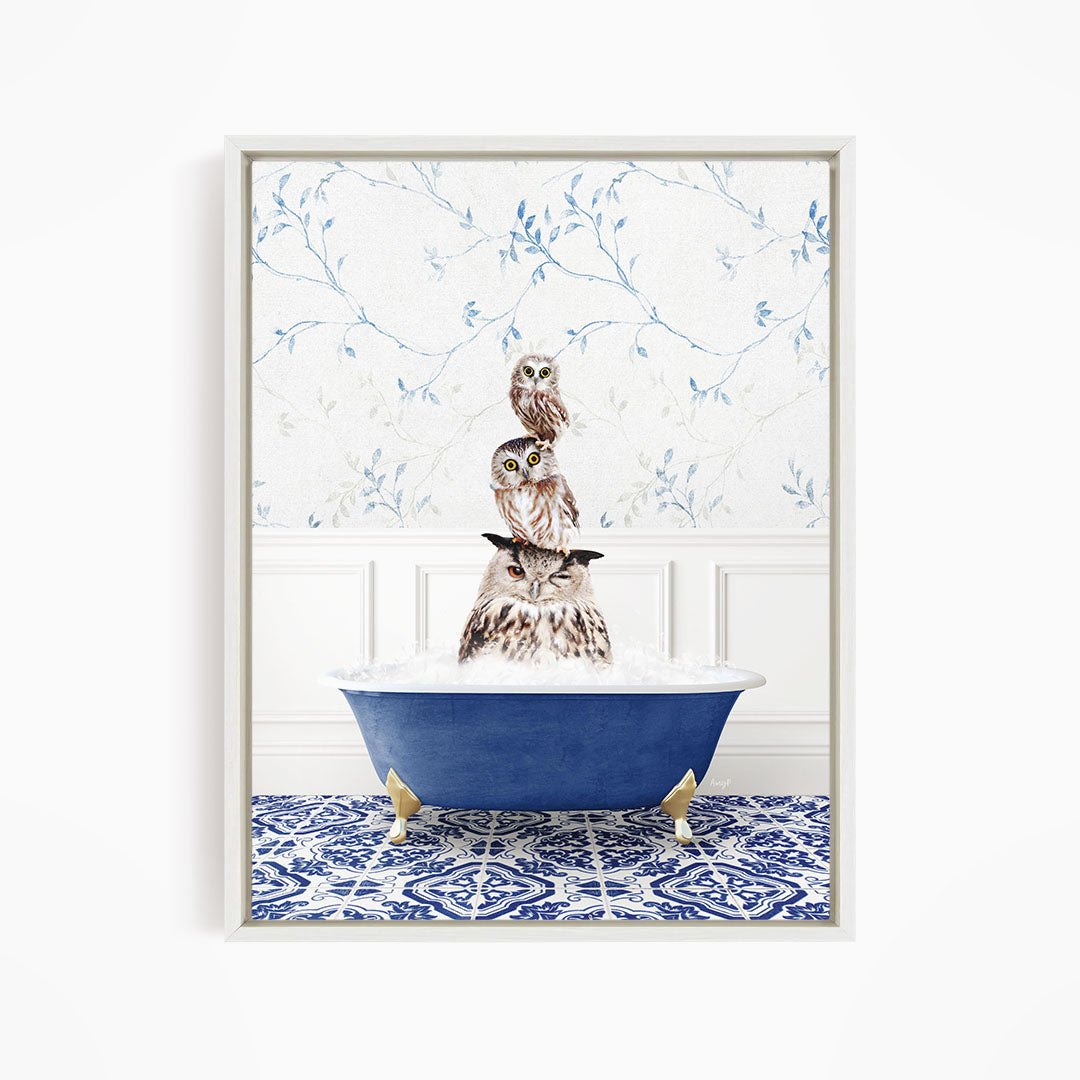 A framed image depicting a group of owls sitting in a blue bathtub, with a patterned tile floor and a floral wallpaper in the background.